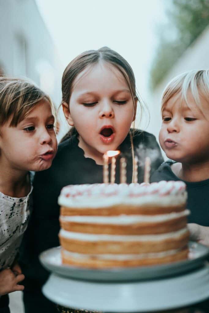 Niño y niña soplando las velas de una tarta de cumpleaños