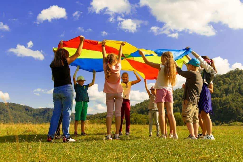 Niños jugando con un paracaídas de colores sobre el césped