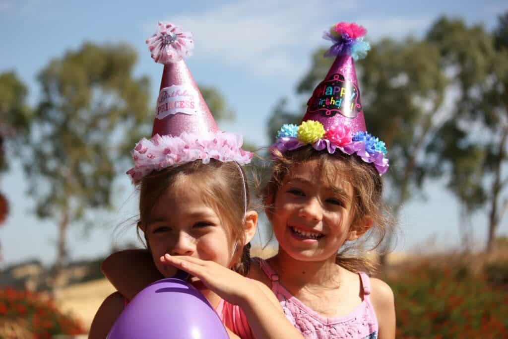 Niñas con globos y gorro rosa en una fiesta de cumpleaños